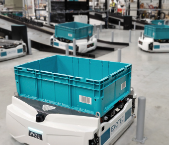 White mobile robot carrying teal tote in warehouse