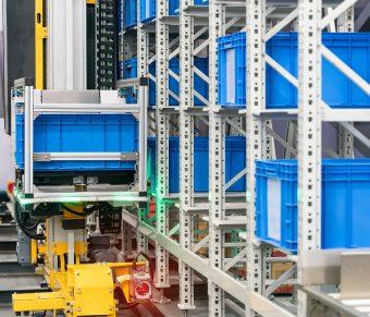 Metal racking storing blue totes and yellow shuttle system grabbing a tote